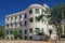 A low-rise deserted 1930s hotel with a decayed facade and green wooden window shutters under the summer blue sky