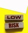 Low risk words wooden blocks on yellow. Business investment risks concept