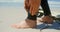 Low section of active senior Caucasian male surfer tying surfboard leash on her leg on the beach 4k