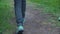 Low section of boy in jeans and sneakers walking on path