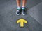 Low Section of Kid Standing In Front Of Yellow Directional Arrow