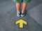 Low Section of Kid Standing In Front Of Yellow Directional Arrow