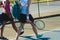 Low section of multiracial female players walking with backpacks and rackets at tennis court