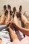 Low section of senior multiracial couple holding hands sitting barefoot at beach on sunny day