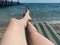 Low Section Of Woman On Lounge Chair At Beach By Sea Against Clear Sky