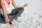 Low section of woman meditating on sand at beach