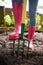 Low section of woman wearing pink rubber boot standing with fork on dirt