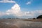 Low tide at sea with rocks on the horizon and a catamaran in the sand without water.