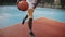 Low view of young afro American athlete has basketball training. Caucasian guy dribbling a ball, throwing and scoring on