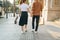 Lower body section of a young tourist couple walking by store windows and holding paper shopping bags in a destination city