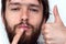 Lower part of beard man`s face with herpes on his lips and hand putting cream on it with thumbs up. concept of treatment for