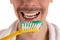 Lower part of face of man with big yellow toothbrush and white towel on shoulders