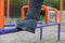 The lower section of a mature man engaged in restorative gymnastics on the sports ground. The man`s legs are standing on the blue