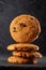 Lowkey picture of stack of chocolate chip cookies on dark stony background, close-up, shallow depth of field