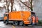 LUCERNE, SWITZERLAND - January 2021: orange cargo garbage truck driving through city streets, collecting garbage from bins, waste