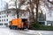 LUCERNE, SWITZERLAND - January 2021: orange cargo garbage truck driving through city streets, collecting garbage from bins, waste