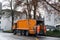 LUCERNE, SWITZERLAND - January 2021: orange cargo garbage truck driving through city streets, collecting garbage from bins, waste