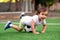 Lucky goalkeeper: little football player caught soccer ball, goalposts in background. Toddler boy lying on belly on soccer ball