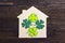 Lucky home symbol with four-leaf clover on wooden background.