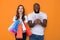 Lucky interracial couple in white T-shirts posing for camera in studio