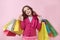 Lucky young long-haired girl holding in hands lot of colorful shopping bags with shopping with a satisfied expression on her face