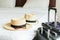 Luggage and hat of a couple on bed in modern hotel room with windows, curtains. Travel, relaxation, journey, trip and vacation