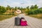 Luggage in the middle of the street with an airplane in the background.