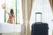 Luggage in modern hotel room with happy young adult female relaxing nearly window, asian woman tourist looking to beautiful nature