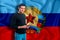 Luhansk People`s Republic flag on the background of the texture. The young man smiles and holds a smartphone in his hand. The