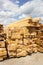 Lumber warehouse in the open air. Wooden beam, planks of wood, stacked in stacks. Sunny day, blue sky with clouds