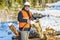 Lumberjack with ax near pile of logs in winter