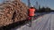 Lumberjack with chainsaw talking on phone near snow covered logs