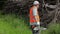 Lumberjack with chainsaw talking on smarth phone near the pile of branches