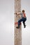 LUMBERJACK CLIMBING LARGE POLE WITH CLOUDY SKY IN BACKGROUND