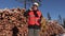 Lumberjack with rope and ax talking on phone near pile of logs in winter