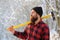 Lumberjack in the woods with an ax. Bearded man in hat with a hatchet. Handsome man, hipster. Lumberjack brutal bearded