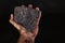 A lump of brown coal in the palm of your hand. Fuel material for heating single-family houses