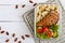 Lunch box: rotini with baked chicken breast and salad on a white wooden background. Top view, flat lay.