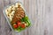 Lunch box: rotini with baked chicken breast and salad on a wooden background. Top view, flat lay.