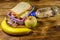 Lunch box with sandwiches, bottle of water, banana and apple on a wooden table