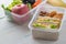 Lunch box set of Egg salad with sandwich slices in box and almond, peanut butter cracker with fruits and vegetables in boxs.