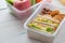 Lunch box set of Egg salad with sandwich slices in box and almond, peanut butter cracker with fruits and vegetables in boxs.