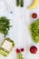 Lunch box and set of ingredients for making school lunch: vegetables, fruits, bootle of water on white wooden table. Healthy