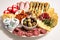 Lunch meal or appetiser with a single dish of salami, pepperoni, brie cheese, ham. Dinner plate or appetizer with salumi, cheeses