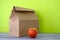 Lunch packed in a brown paper bag with red apple