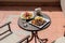 Lunch on the plate with lamb, potato and salad on the table outside on the balcony. Spring or summer blooming trees and flowers