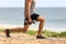 Lunge leg workout with dumbbells weights. Fitness man doing lunges training legs on beach summer outdoors with weight