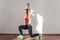 Lunge or split squats with raised hands. Side view of fit woman with bun hairstyle practicing. indoor studio shot illuminated by