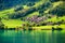 Lungern, canton of Obwalden, Switzerland. A view of rural homes in a green meadow. A lake in a mountain valley.