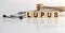LUPUS the word on wooden cubes, cubes stand on a reflective white surface, on cubes - a stethoscope